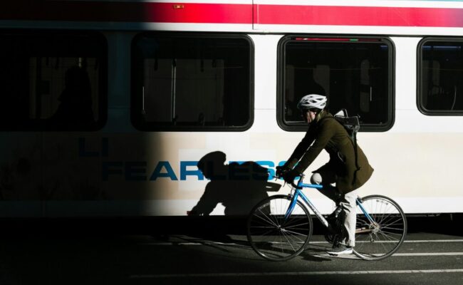 hotos/person-ride-on-city-bike-on-asphalt-road-beside-white-bus-KHrGmSkE6rE