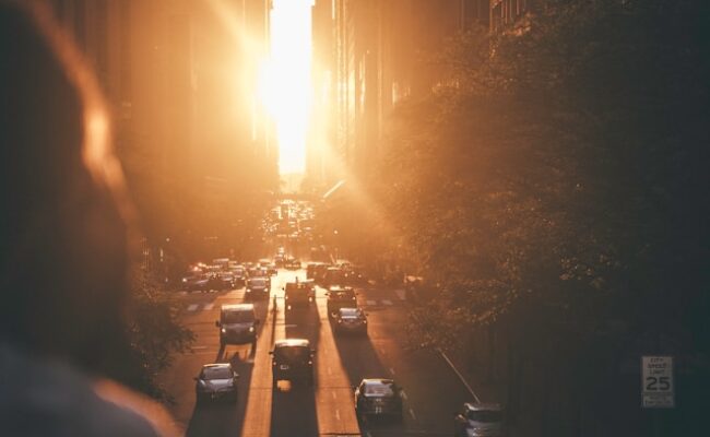 vehicles-passing-between-buildings-during-sunset--K8COreKtUU