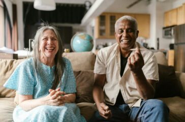 happy-elderly-couple-sitting-on-a-beige-sofa-8139237/