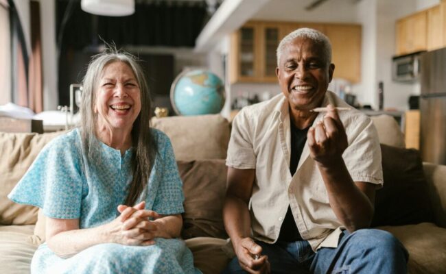 happy-elderly-couple-sitting-on-a-beige-sofa-8139237/