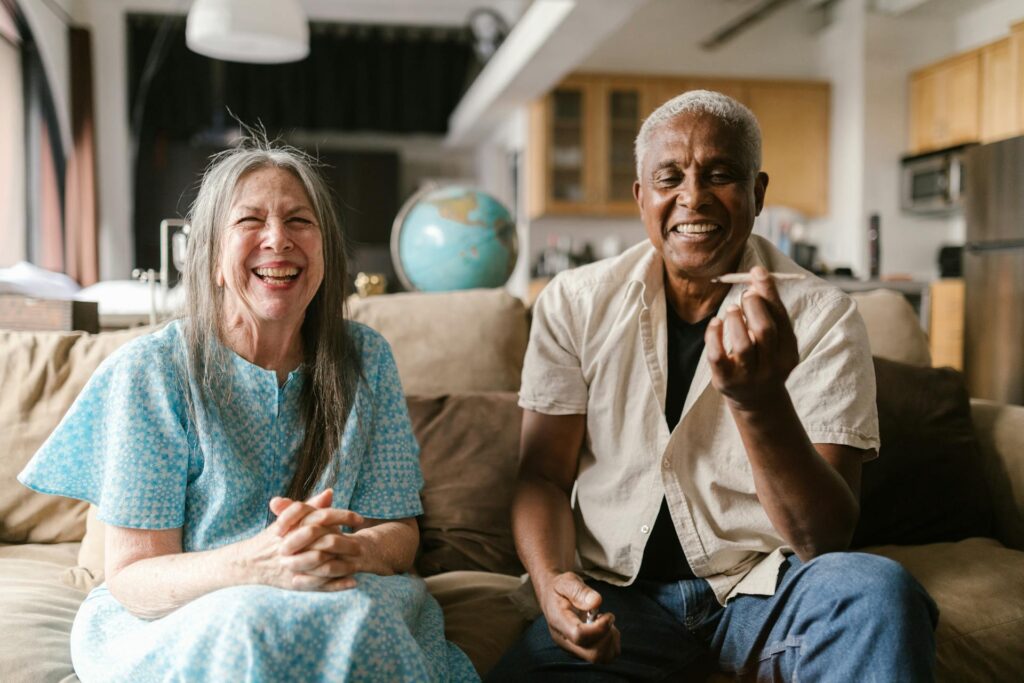 happy-elderly-couple-sitting-on-a-beige-sofa-8139237/