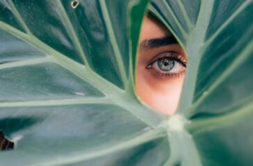 woman-peeking-over-green-leaf-plant-taken-at-daytime-cTKGZJTMJQU