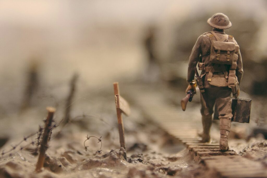 soldier-walking-on-wooden-pathway-surrounded-with-barbwire-selective-focus-photography-qwe8TLRnG8k